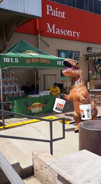 Person in blow up T-rex costume carrying white buckets