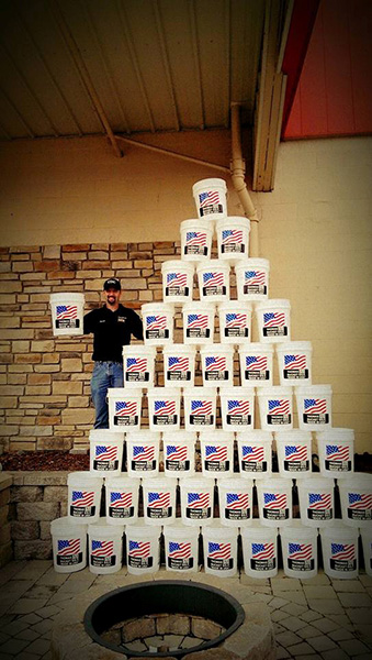 Man standing with stack of white buckets with American Flags on them